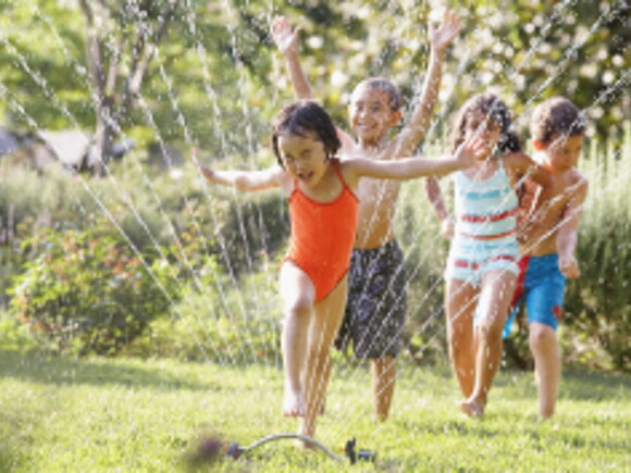 Children jumping through water fountain
