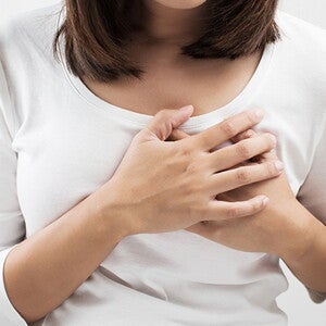 Mother holding her breast in pain, one of her postpartum body changes