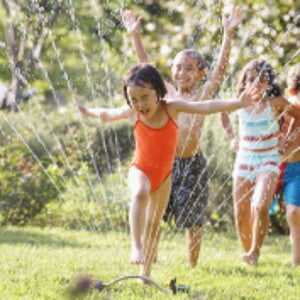 Children jumping through water fountain