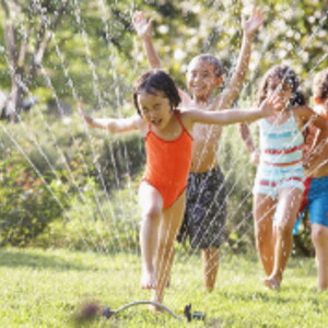 Children jumping through water fountain